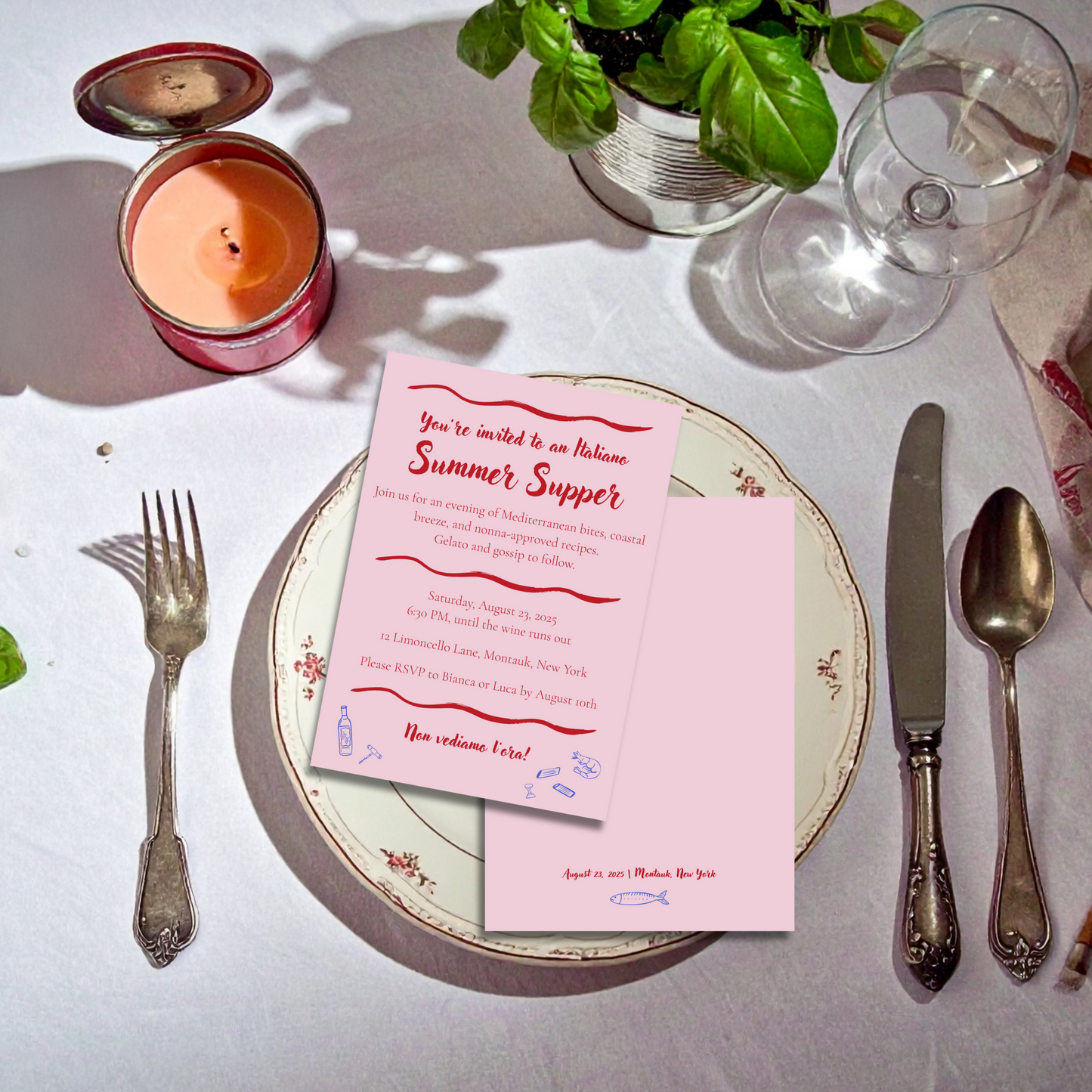 Set table with a pink invitation card on a white surface