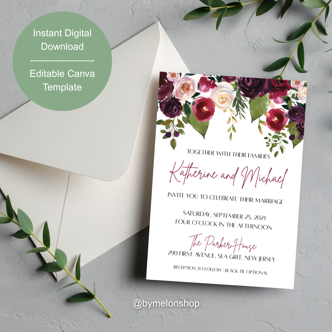 Wedding invitation card with floral design on a gray surface with leaves.