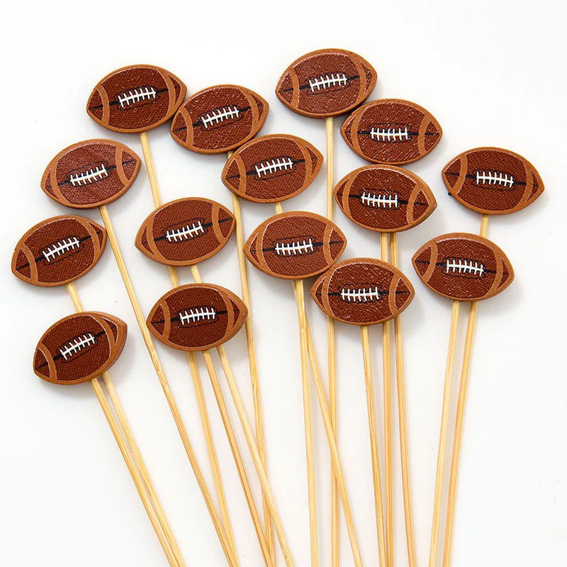 Football-shaped drink stirrers on wooden sticks against a white background