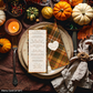 Thanksgiving table setting with pumpkins, candles, and a menu card