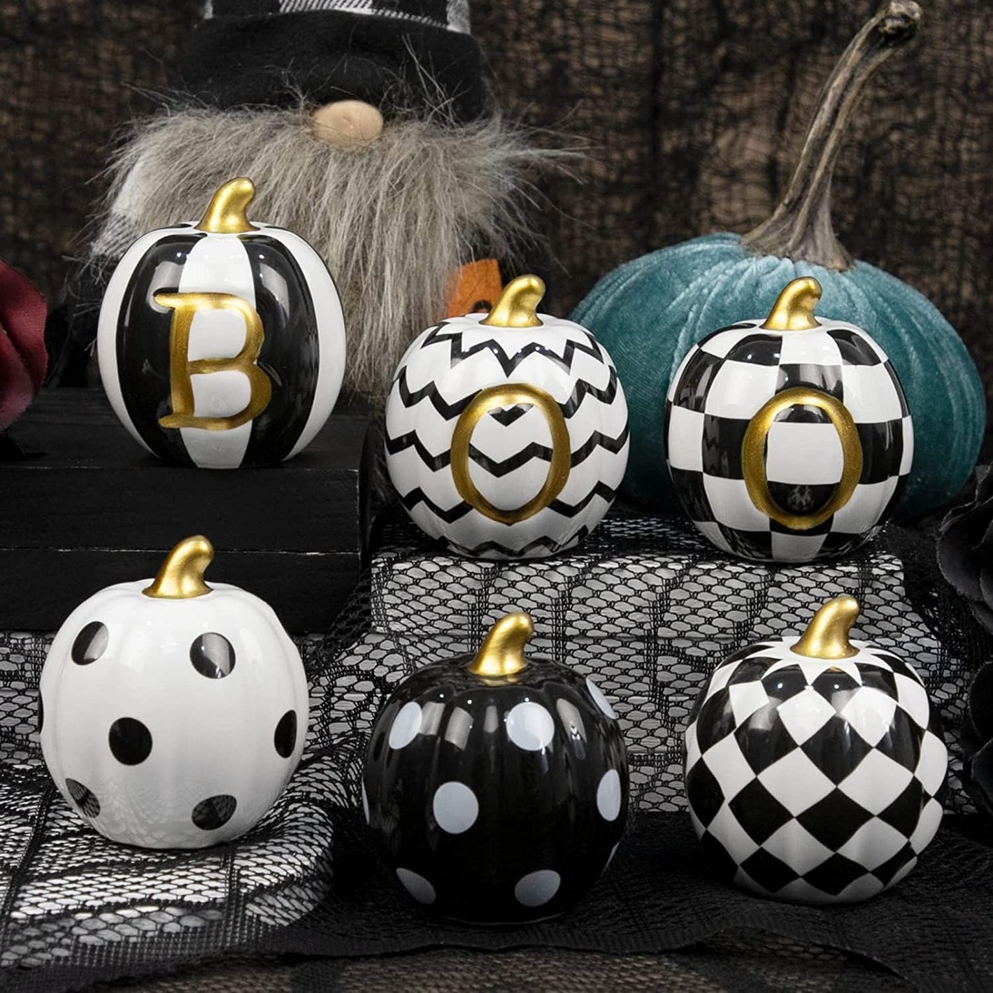 Decorative pumpkins with black, white, and gold patterns on a textured surface.