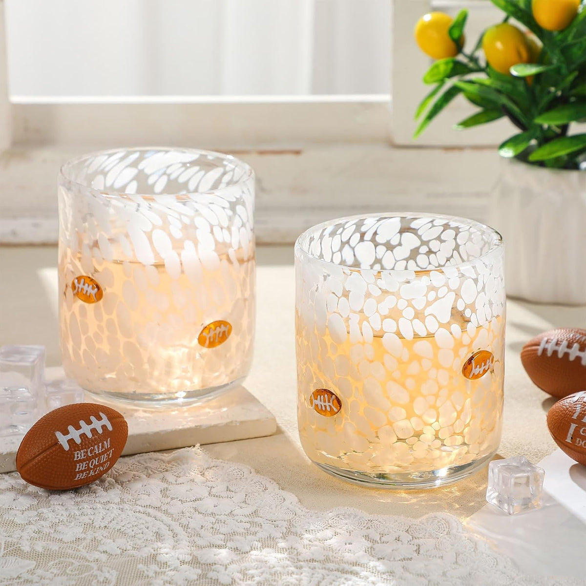Two juice cups with decorative glass on a table with football-themed decor.