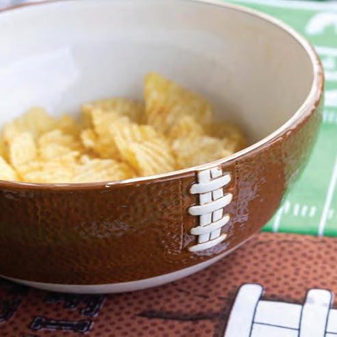 Football-shaped bowl filled with chips on a sports-themed mat