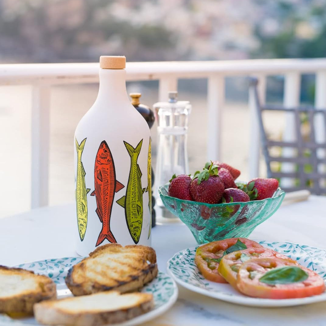 Decorative bottle with fish design on a table with food and a scenic background