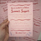 Hand holding a pink invitation card with red text and decorative elements on a matching background.